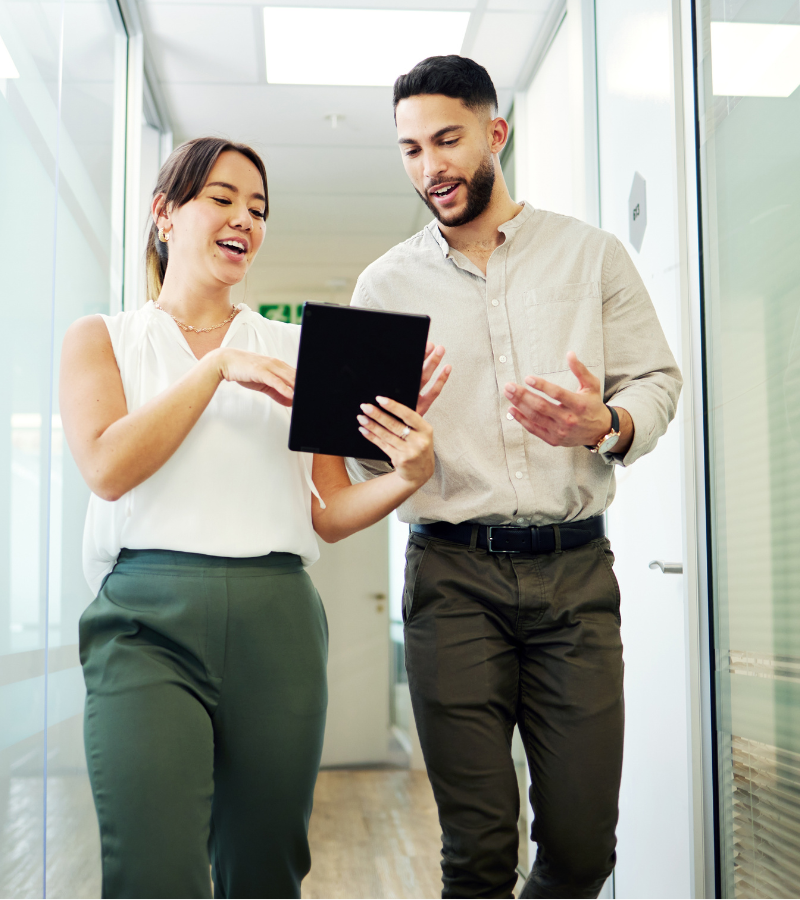woman and man walking in workspace hallway woman and man walking in workspace hallway