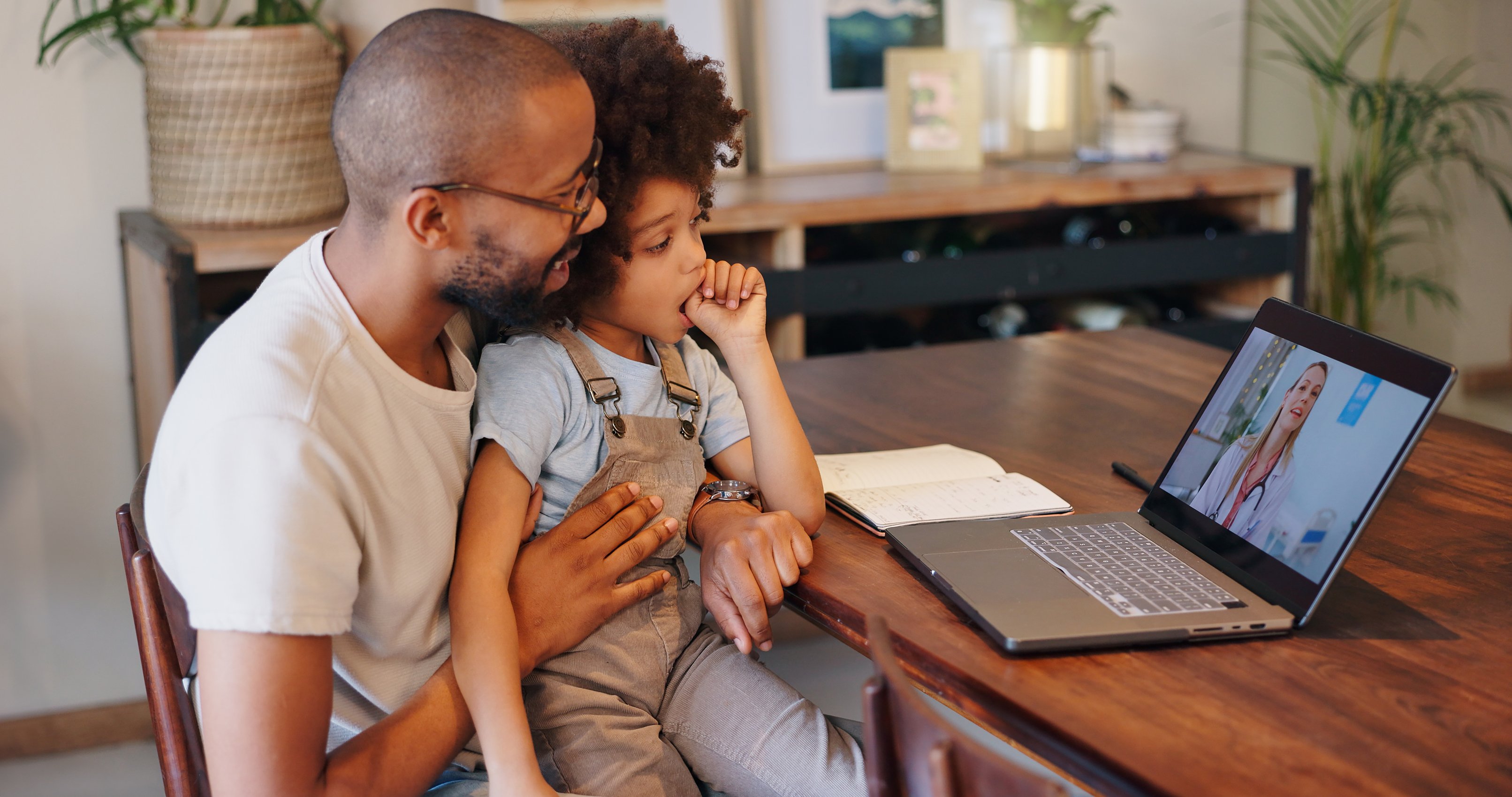 man and child speaking with an urgent care specialist via laptop