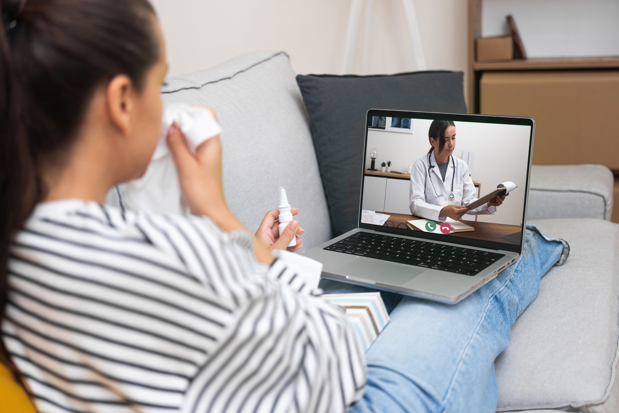 Woman talking to virtual care physician while blowing her nose Woman talking to virtual care physician while blowing her nose